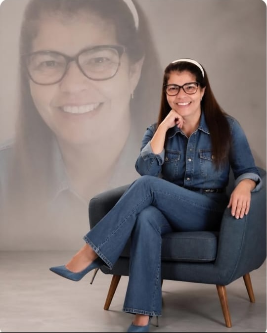 Cida Sena sentada em uma poltrona, em pose acolhedora